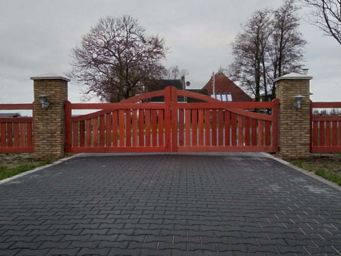 Oprit naar woonerf afgeschermd door een maatwerk houten toegangspoort.